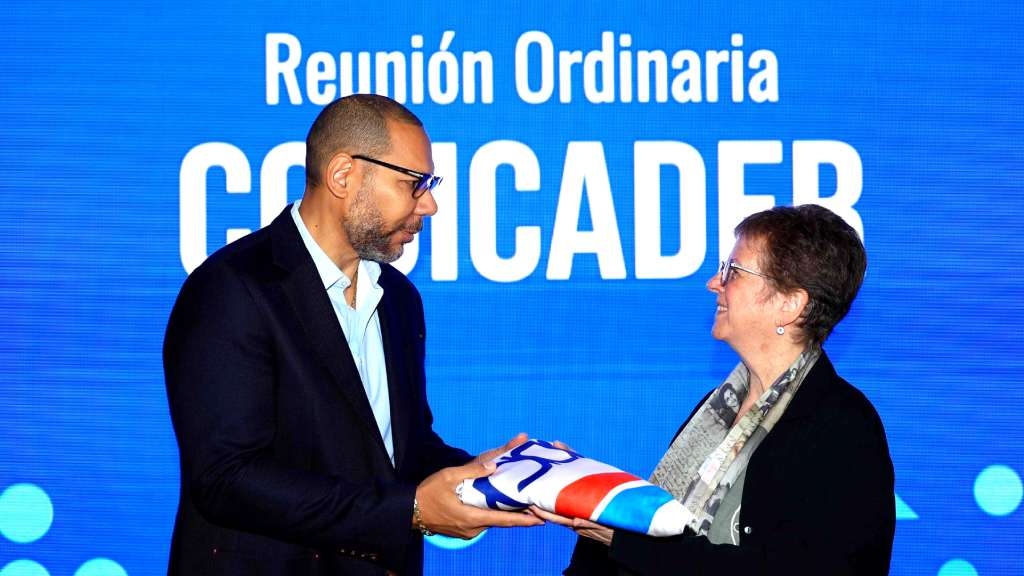 Ana Leticia Aguilar, secretaria general del SISCA, entregó la bandera del Codicader a Yamil Bukele, presidente ad honórem del INDES.